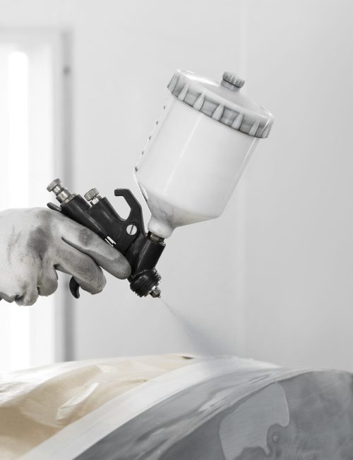 mannlicher maler der gewehr verwendet um auto im geschaft zu malen